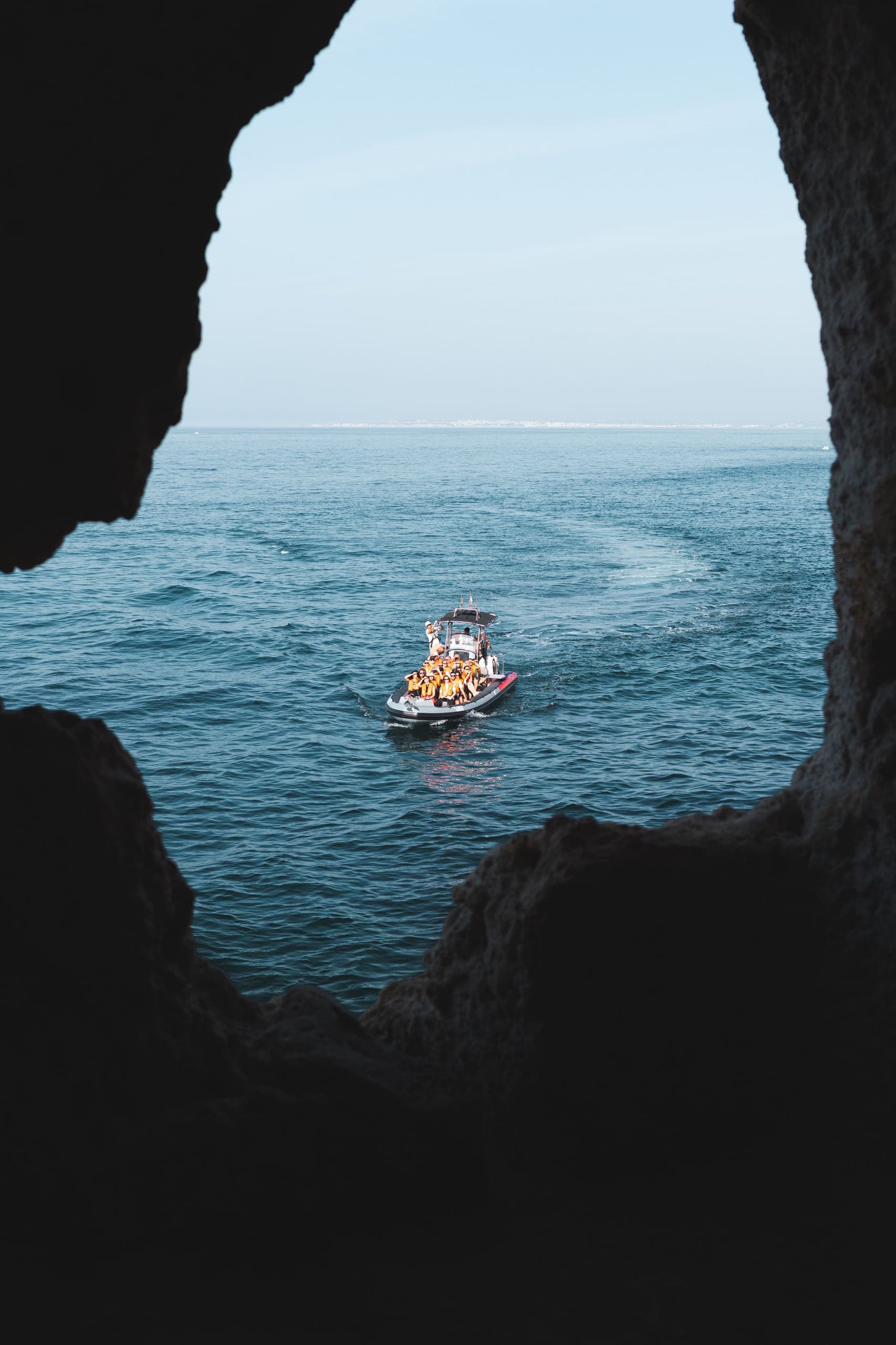A small boat framed by the dark mouth of a sea cave near Carvoeiro in the Algarve
