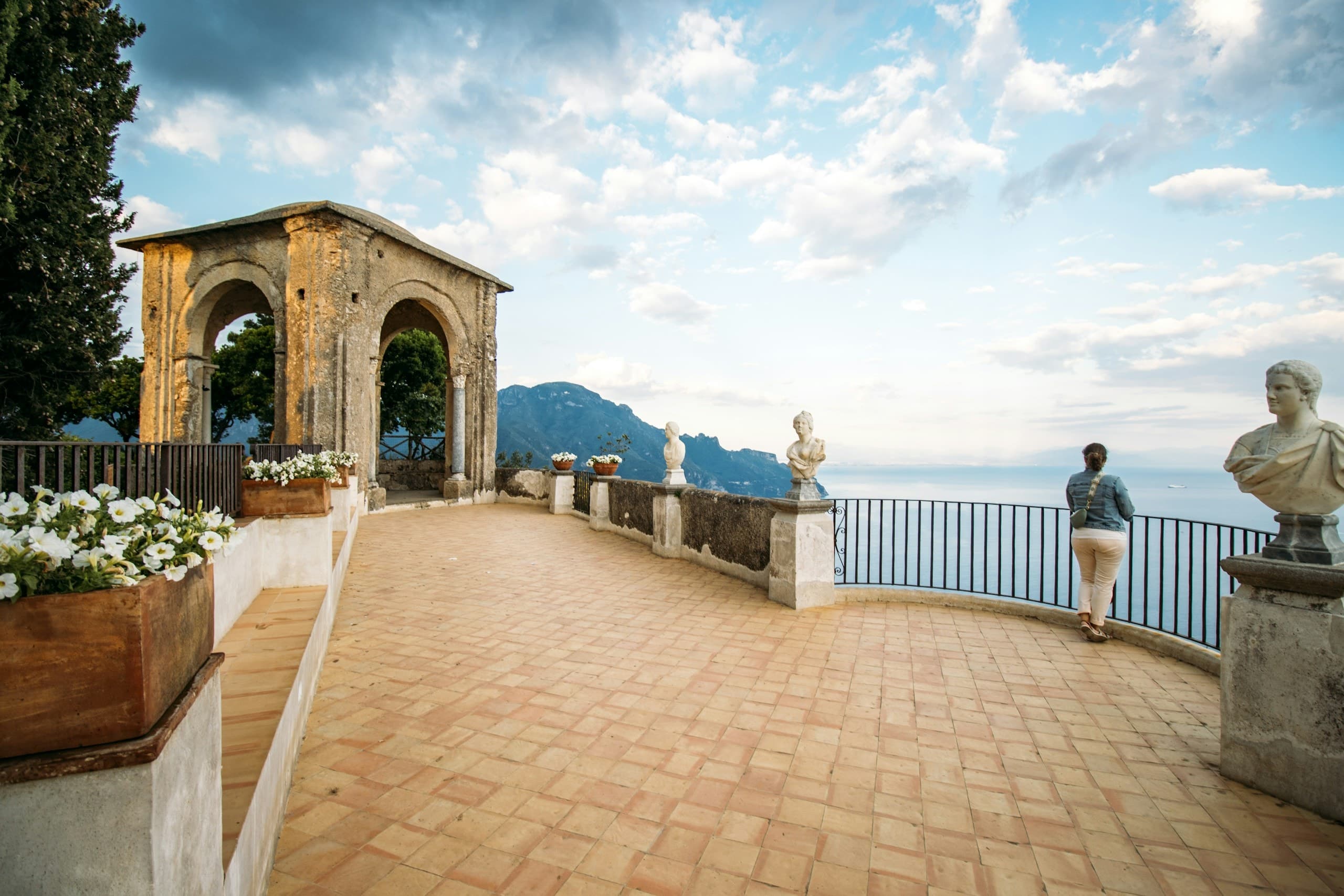 Historic italian balcony with a woman viewing the scenic coastline.