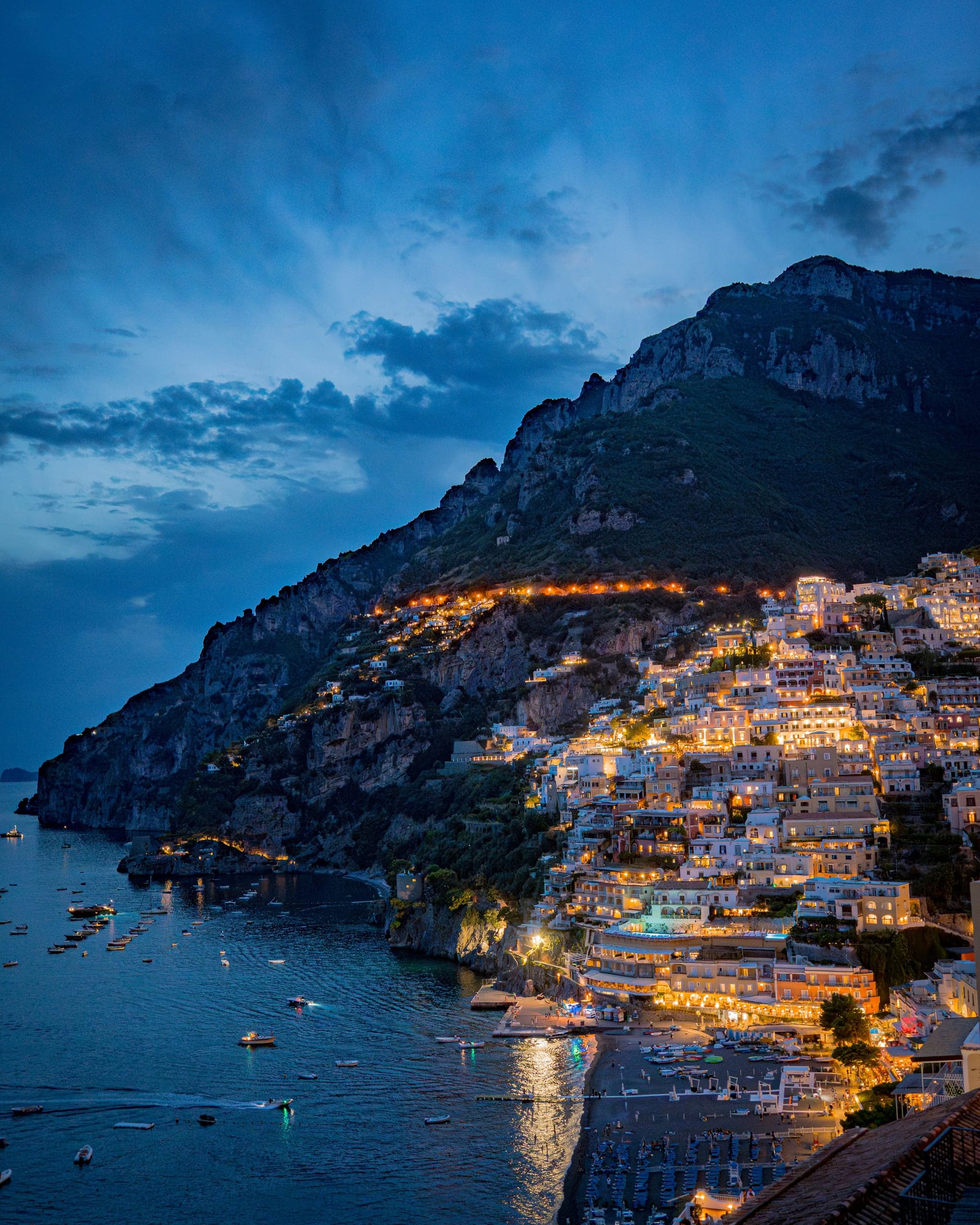 Positano glowing gold against the mountain and deep blue sea just after sunset