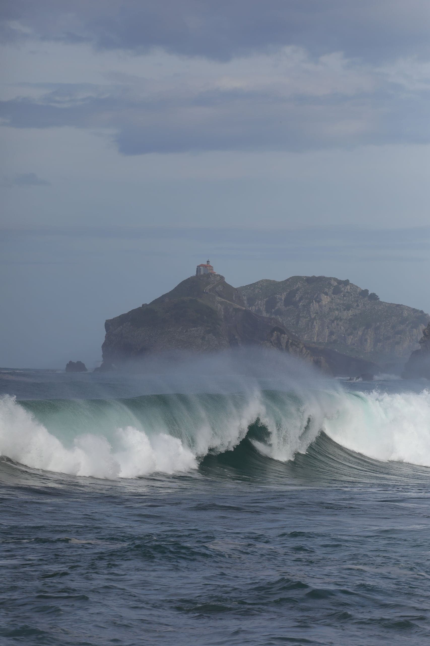 Powerful winter-green waves rise beneath the chapel-topped island of Gaztelugatxe