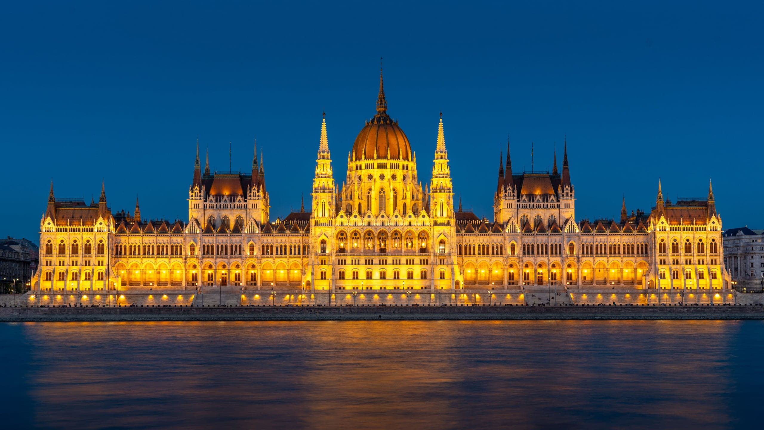 The Hungarian Parliament glowing gold across the deep-blue Danube at twilight in Budapest