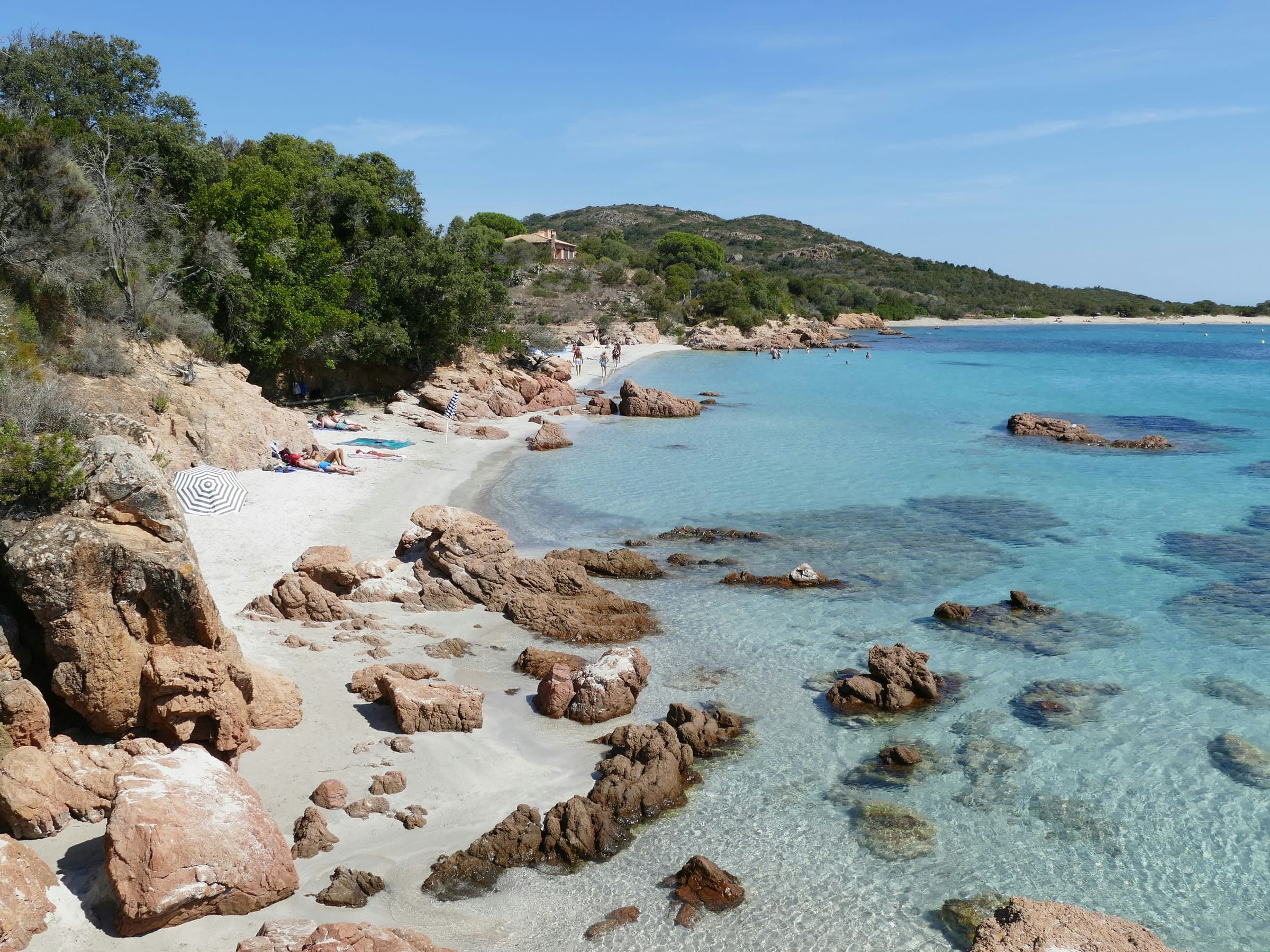 Transparent turquoise water curling around a rocky Corsican beach