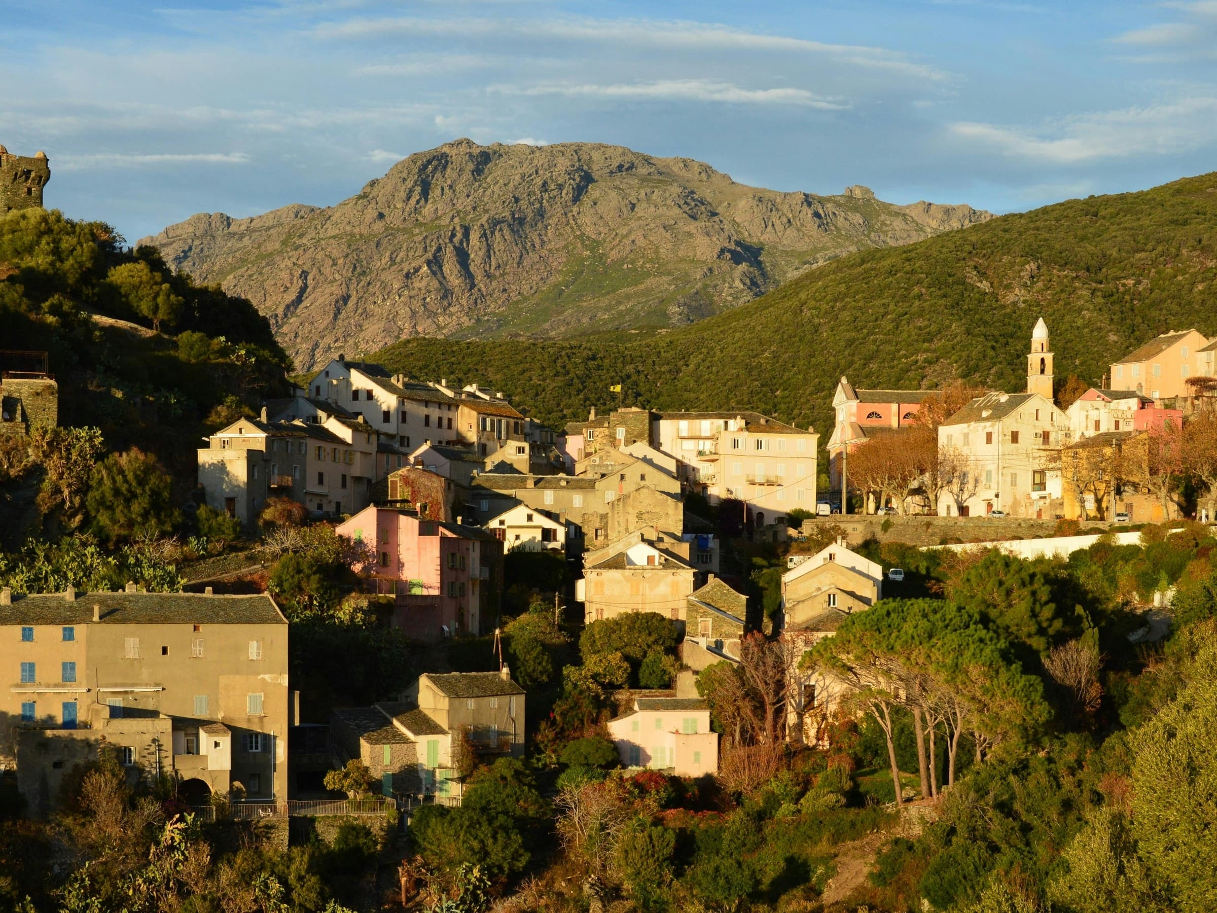 Nonza's warm stone village climbing into Corsica's rugged green mountains