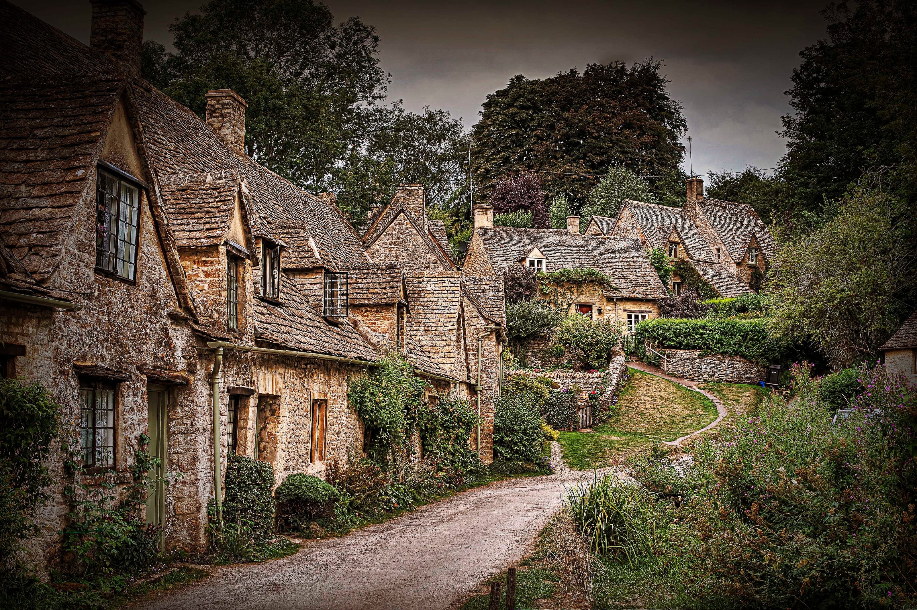 Honey-stone cottages and gardens lining the gentle curve of Arlington Row in Bibury