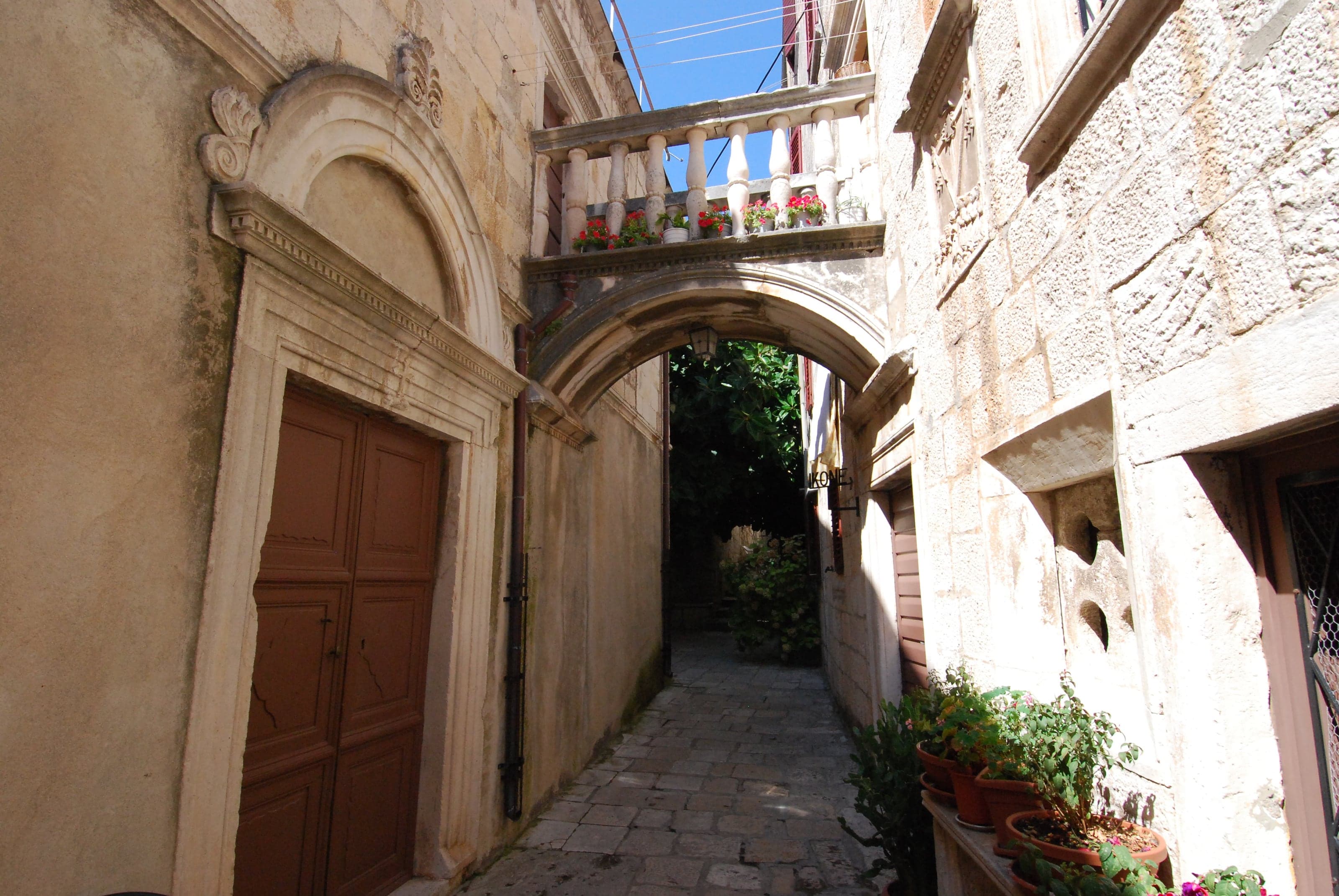 A quiet honey-stone lane passing beneath an arch in Korčula Old Town