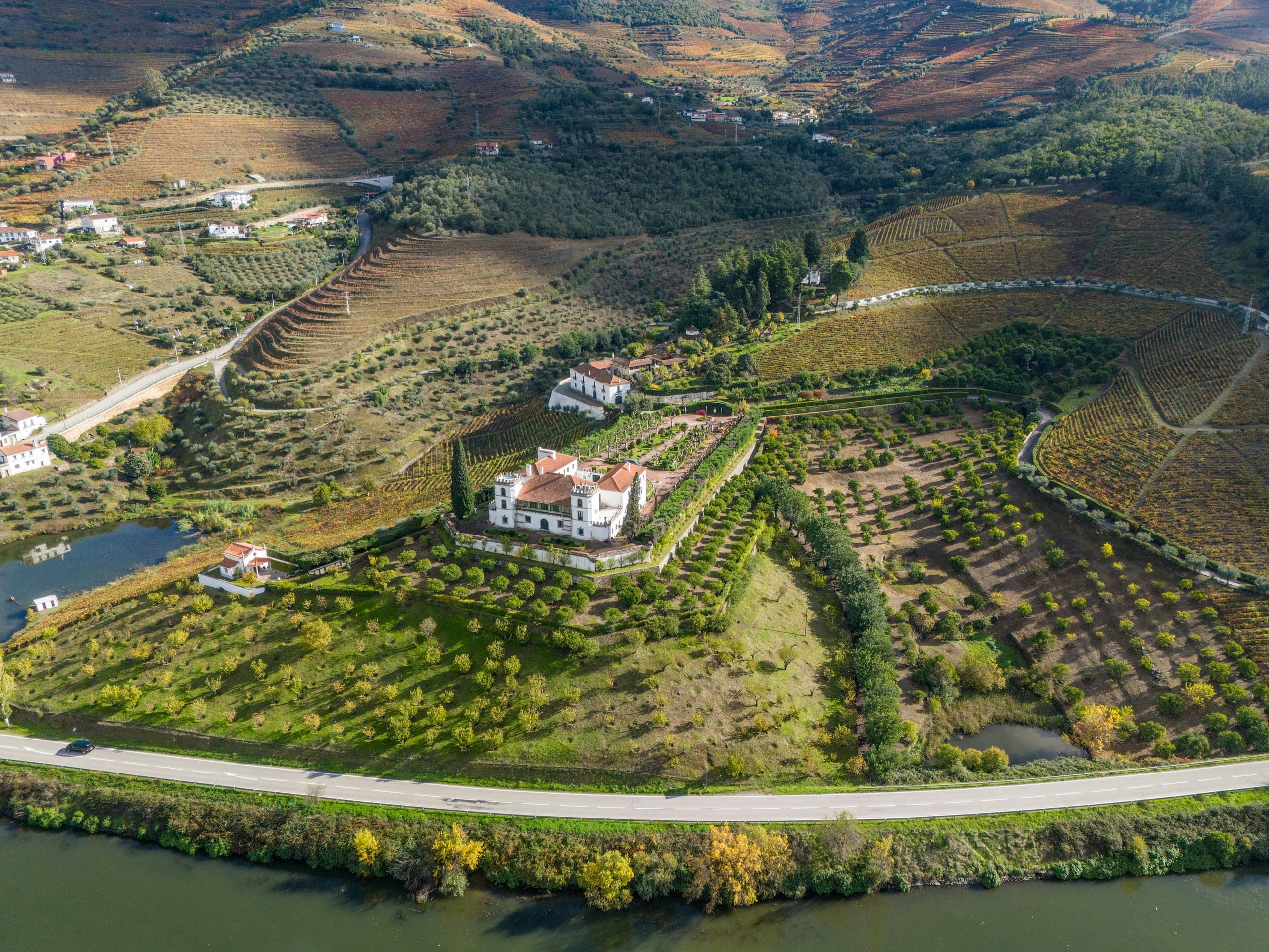 Riverside wine estate and gardens surrounded by autumn Douro vineyards