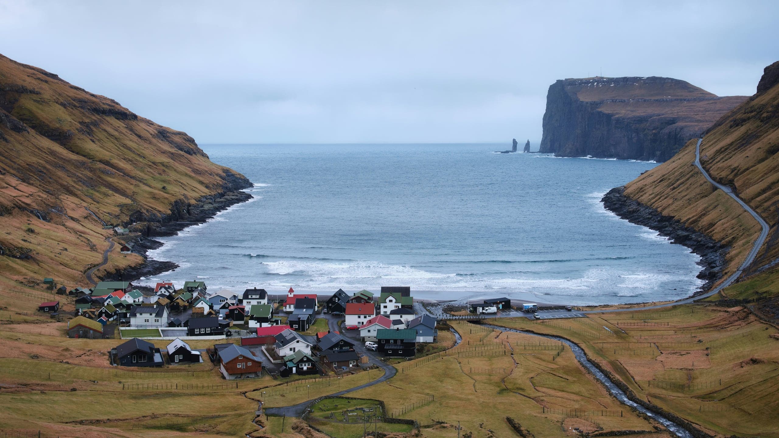 Tjørnuvík village gathered around its surf beach, with Risin og Kellingin sea stacks beyond