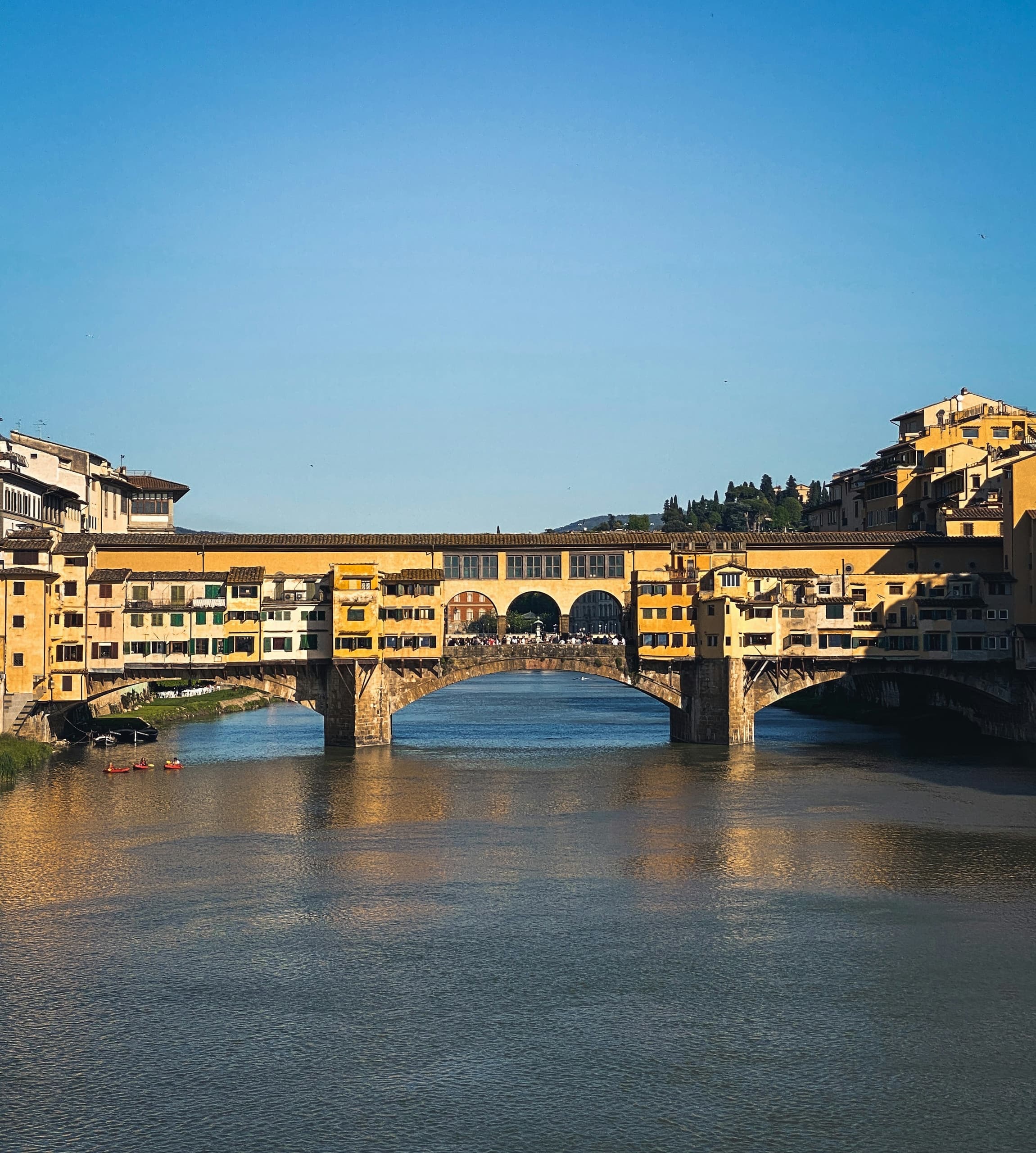 The Ponte Vecchio reflected in the Arno beneath a soft blue Florence sky