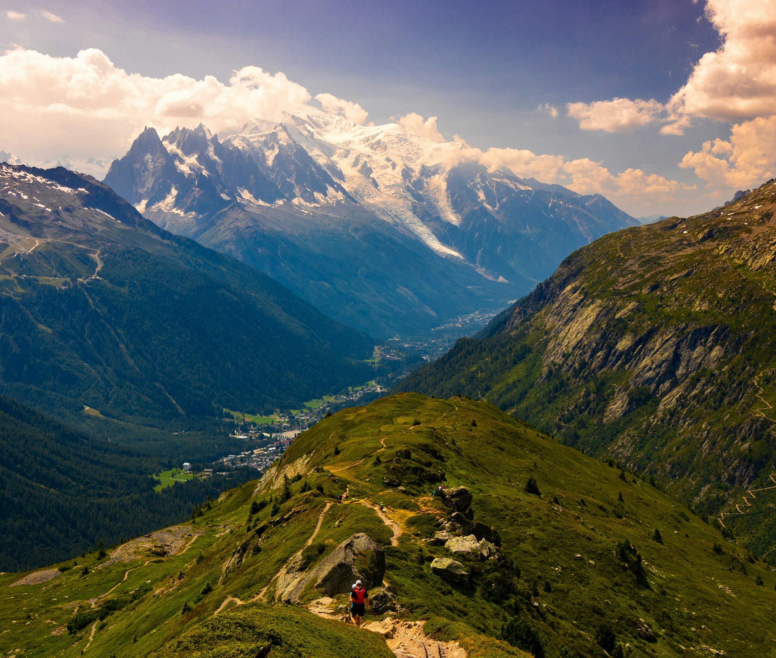 Hikers crossing a green ridge on the Tour du Mont Blanc above Chamonix