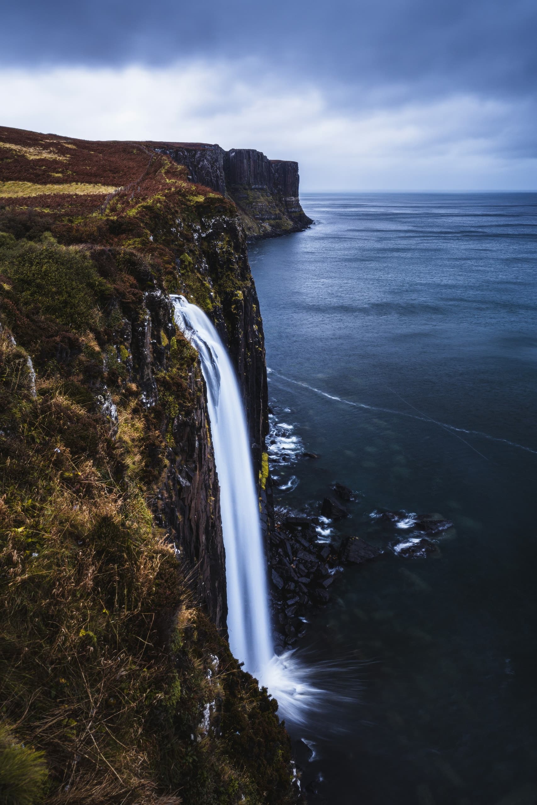 Waterfall cascading down a cliff into the ocean.