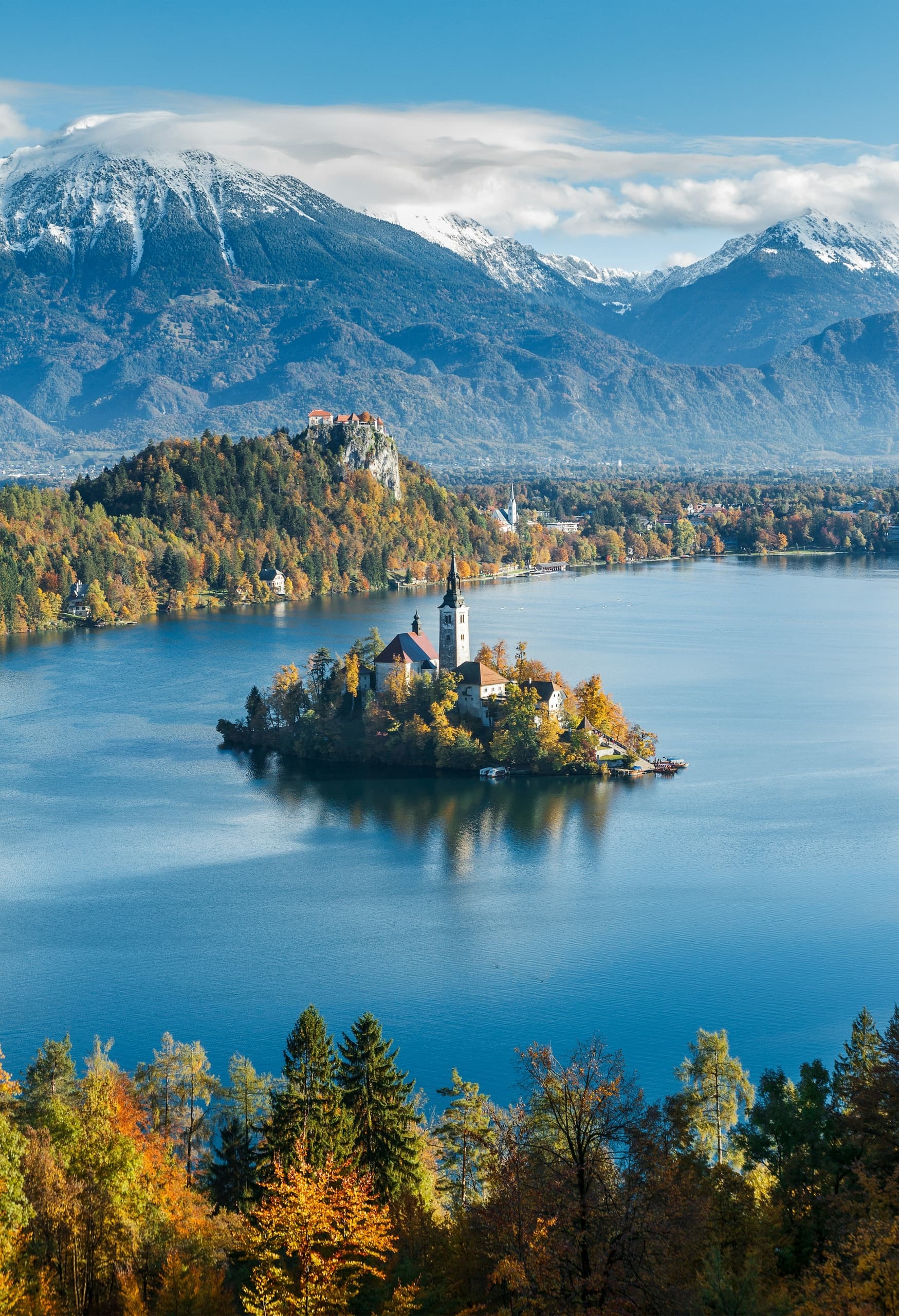 a small island with a building on it surrounded by trees and mountains