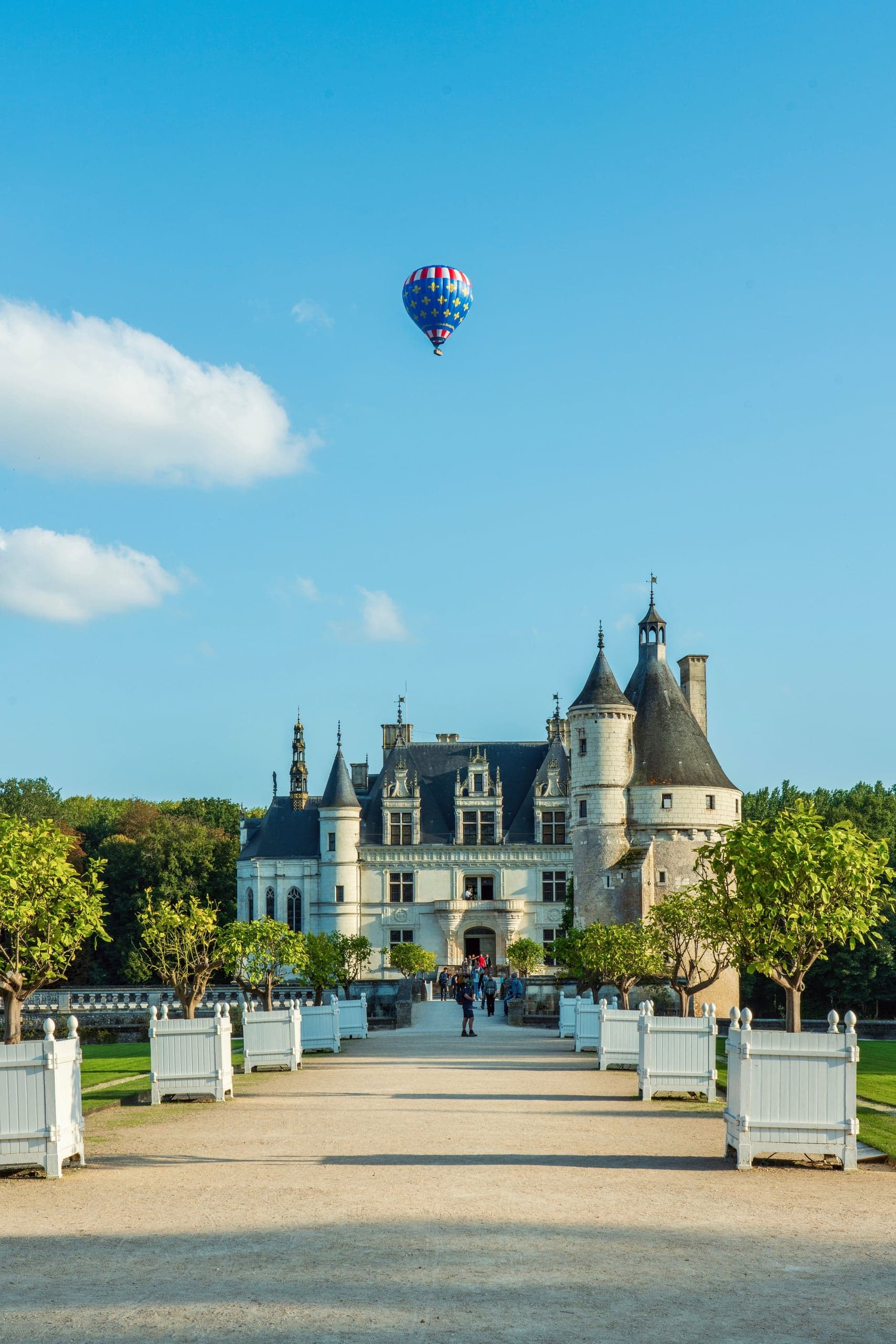 Hot-air balloon floating above a Loire chateau and garden allee