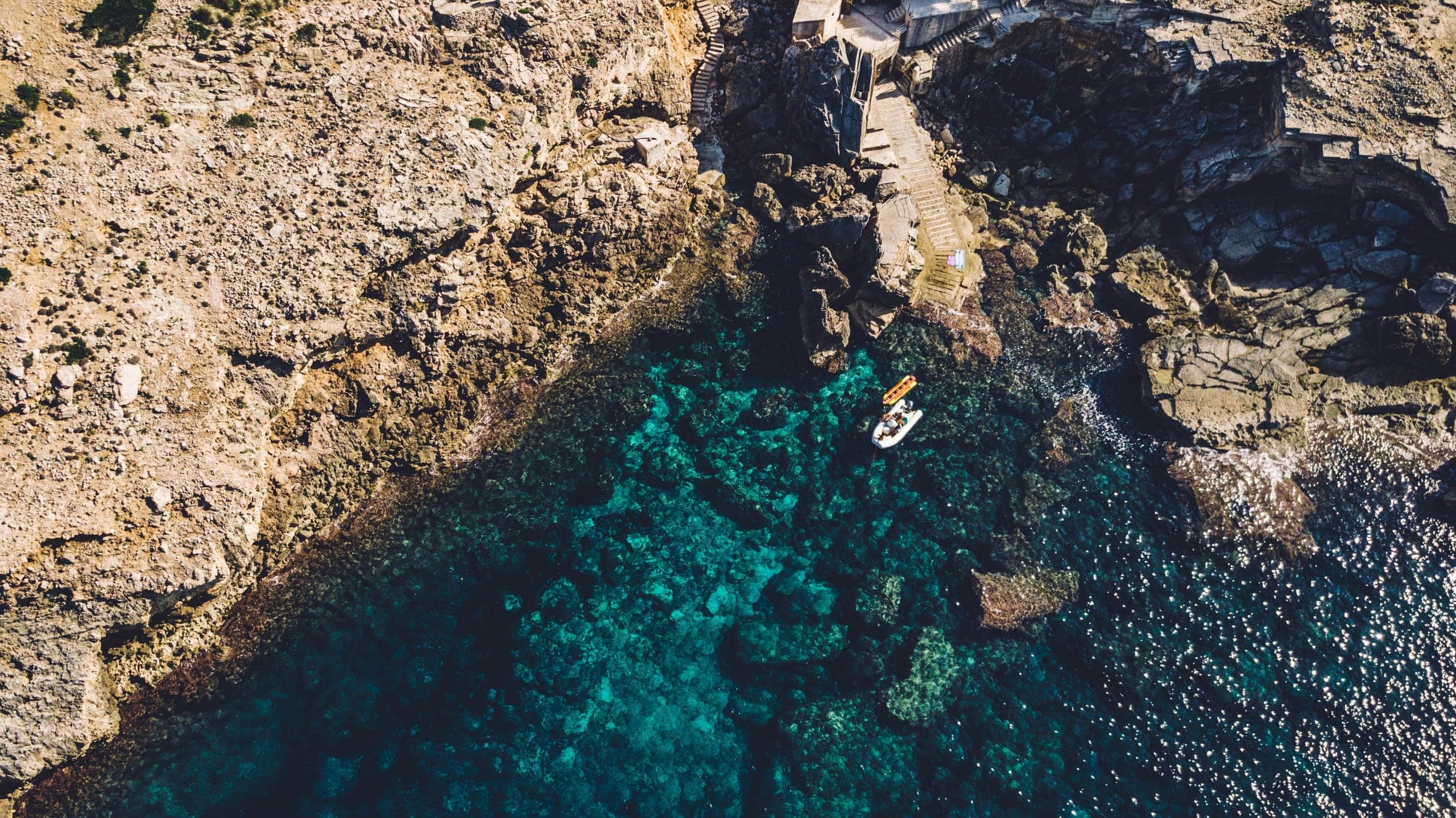 A tiny boat floating in the crystalline water of Cala Sant Vicenc