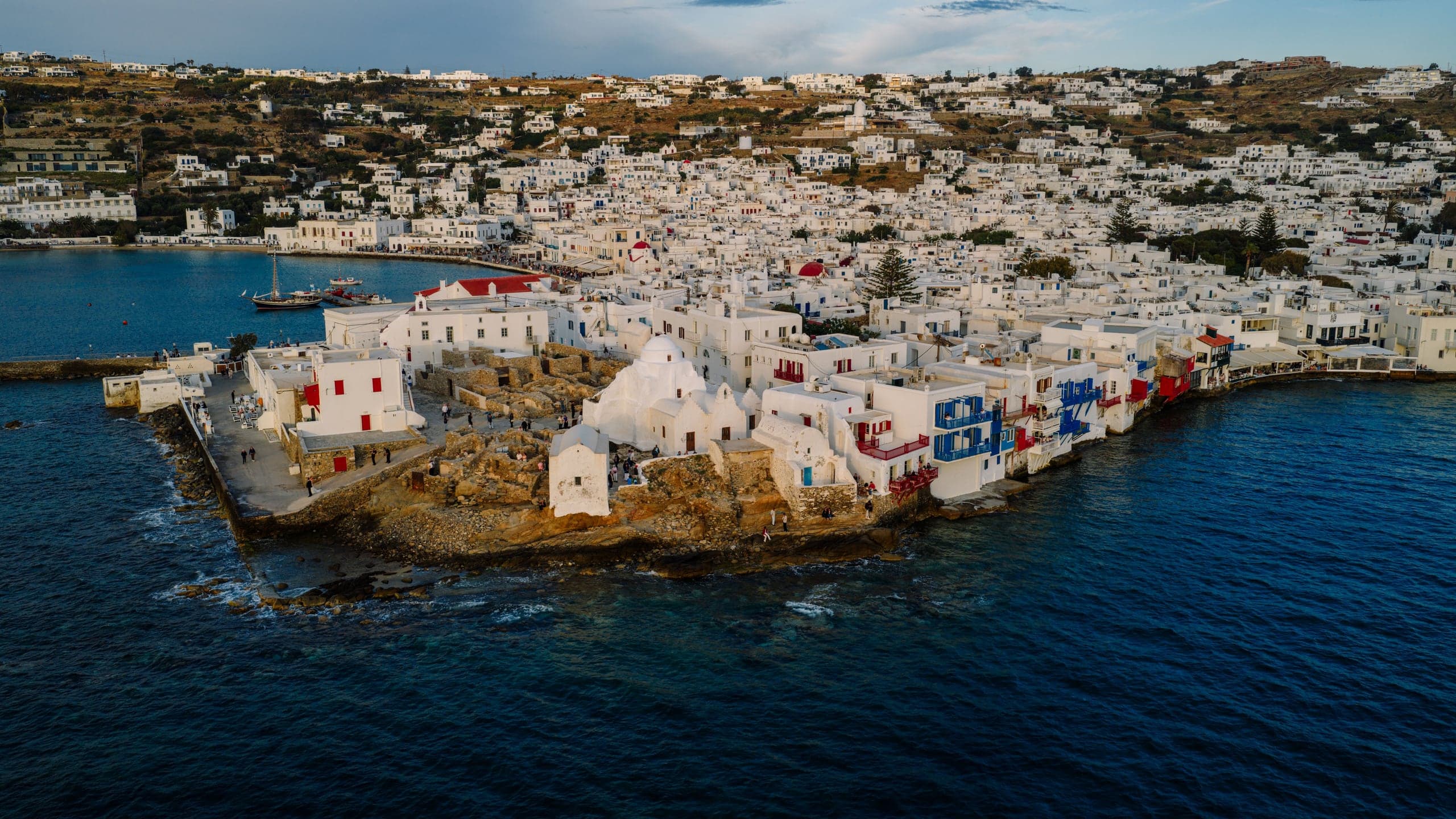 Whitewashed Mykonos Town descending to the dark Aegean waterfront at dusk