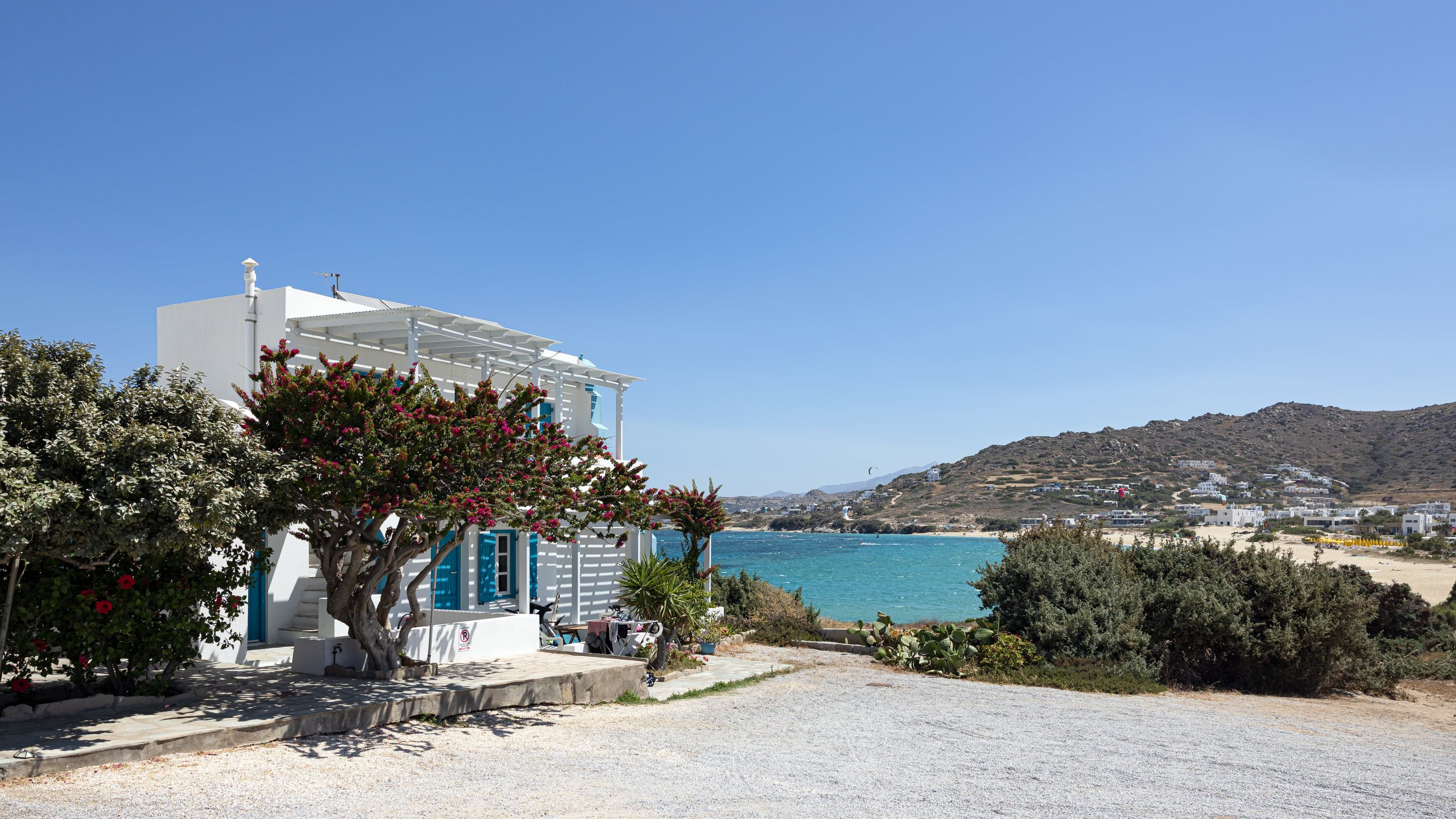 A whitewashed seaside home and bougainvillea overlooking the vivid turquoise bay at Mikri Vigla on Naxos