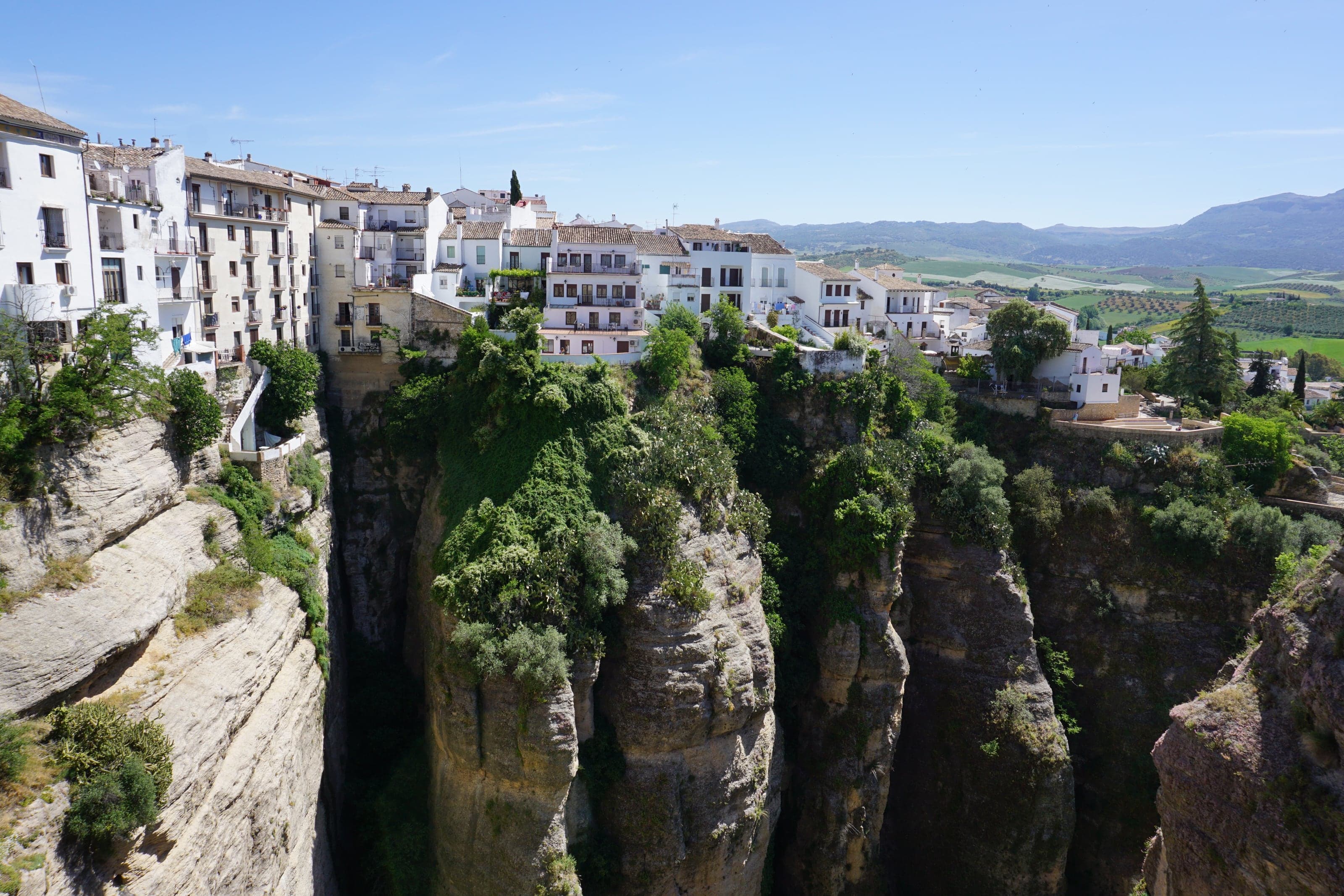Whitewashed houses lining the sunlit rim of Ronda's immense green-and-stone El Tajo gorge