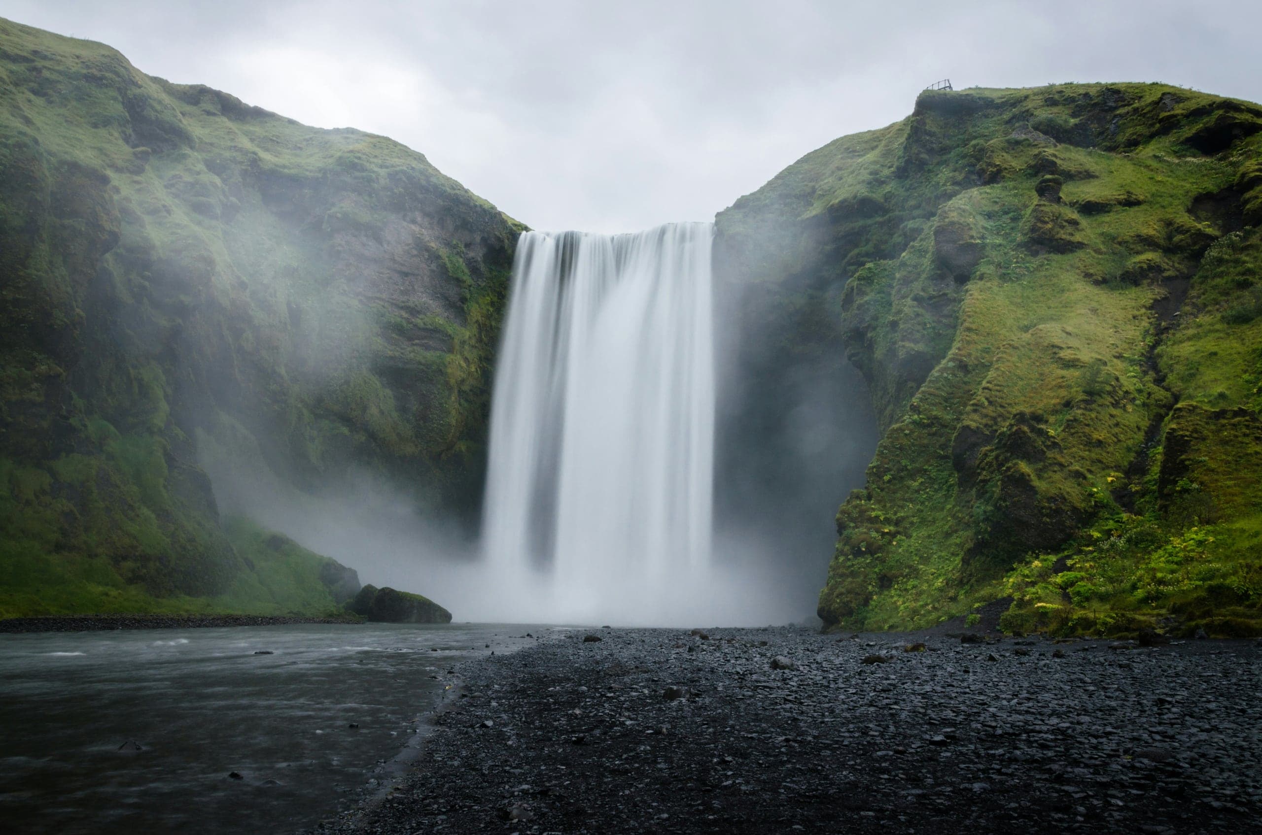 Skógafoss descending from its green escarpment in dawn light