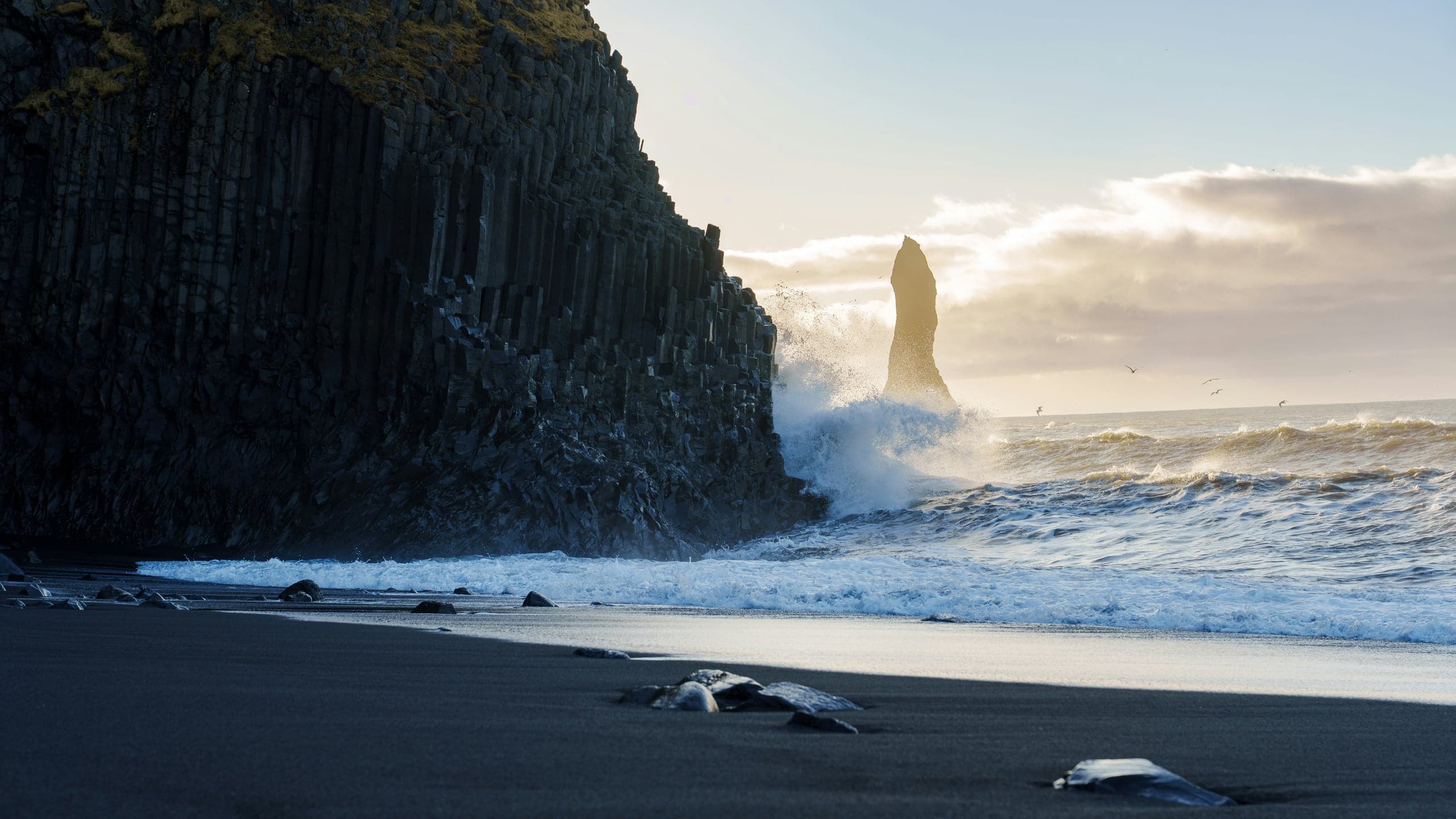 Reynisfjara's black sand, basalt cliff, sea stack, and crashing Atlantic surf