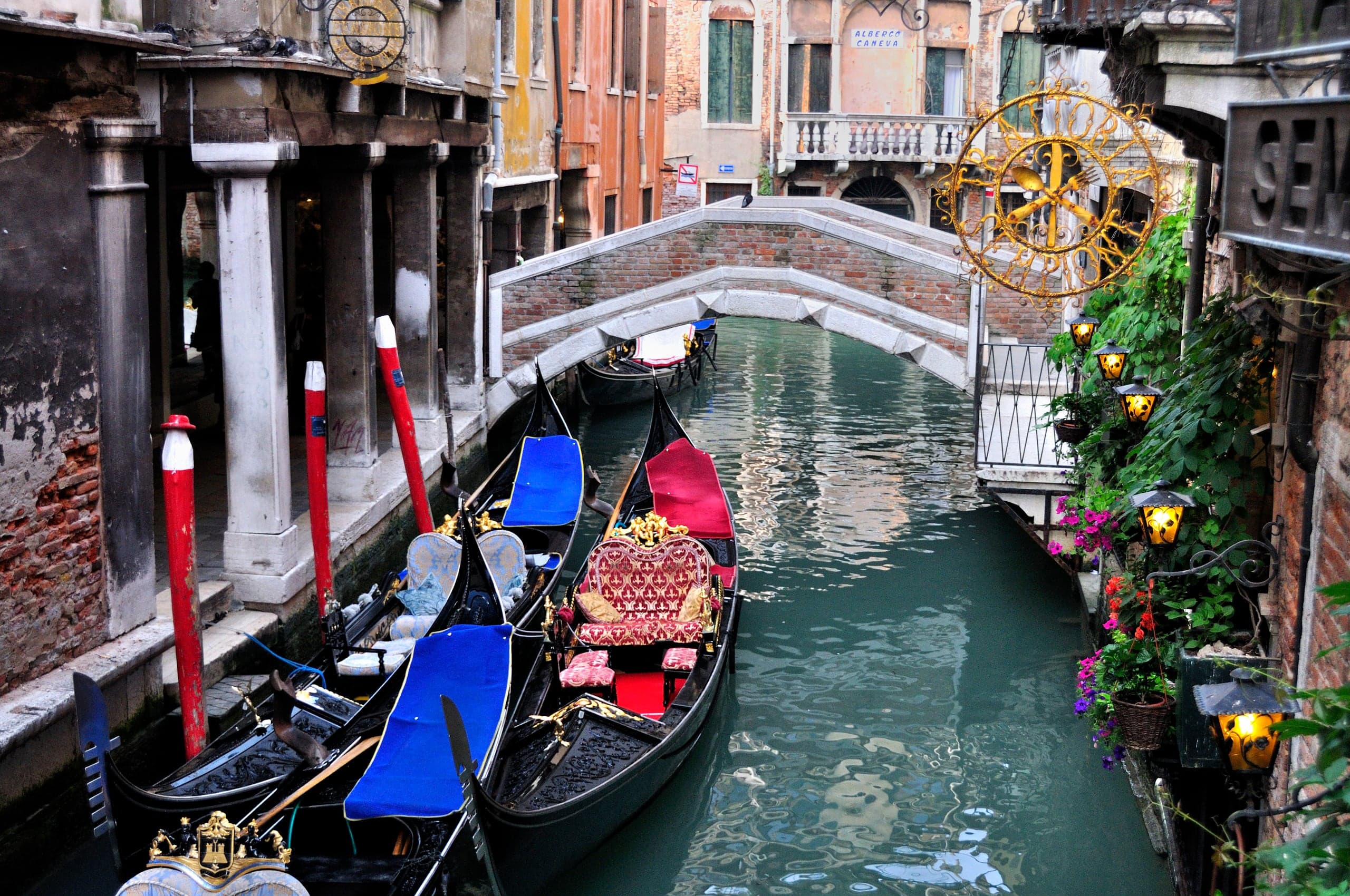 Gondolas moored beneath a small bridge on a narrow Venice canal