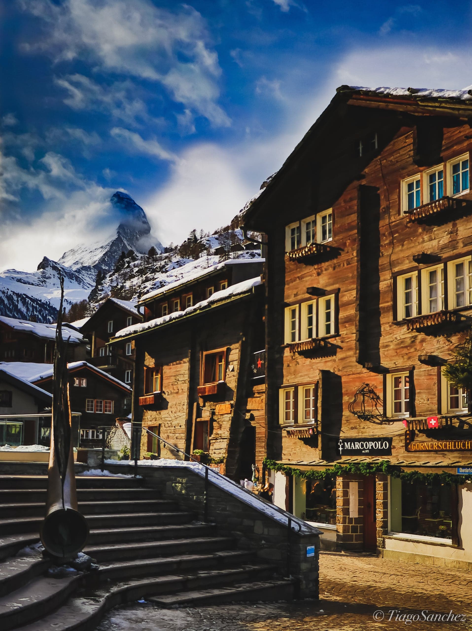 Snowy timber houses in Zermatt frame a cloud-wrapped view of the Matterhorn